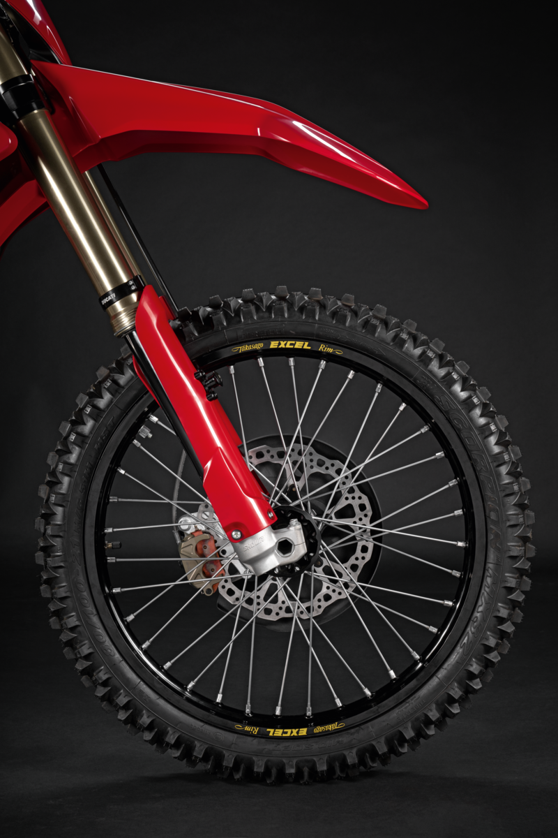 Close-up of a red dirt bike wheel on a black background