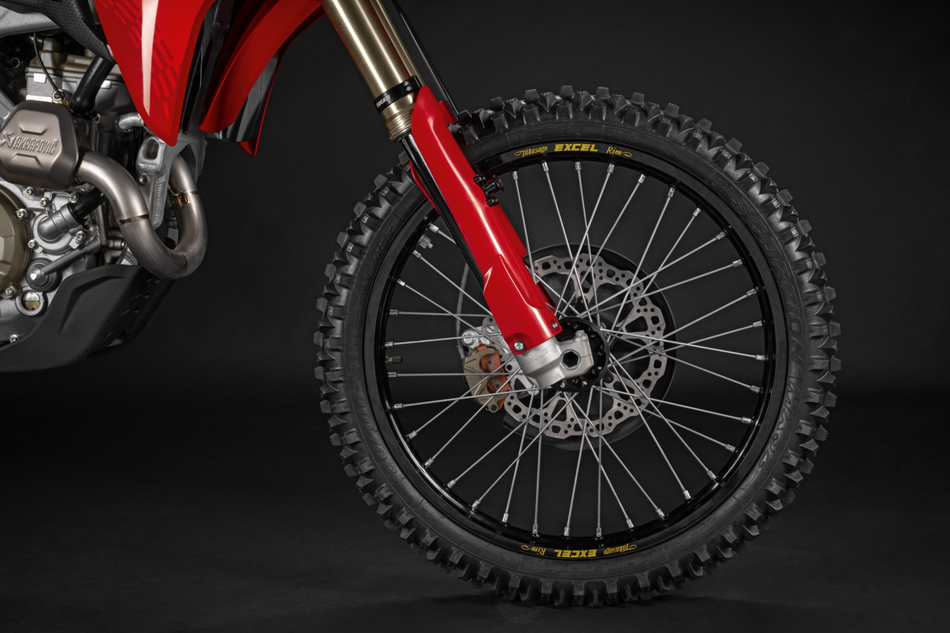 Close-up of a red dirt bike wheel on a black background